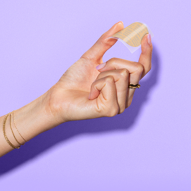 A hand holding the Gwyn Lo birth control patch